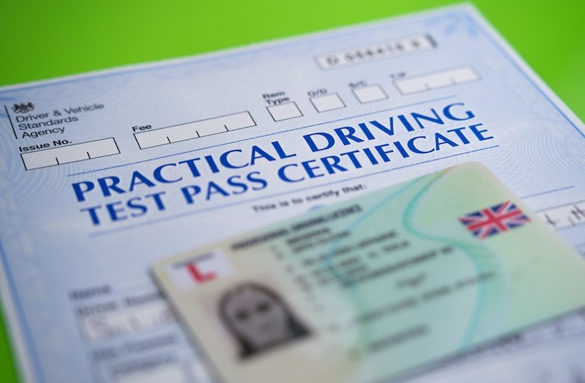 Authentic Practical Driving Test Certificate which is received after passing driving test in the UK and blurred provisional driving licence. Stafford, United Kingdom, April 13, 2022.
